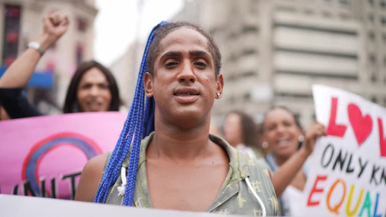 Porträt einer Transgender-Frau, die während einer Demonstration auf der Straße ein Schild hält