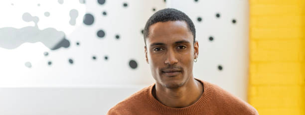 istock Horizontal banner or header with young Moroccan man with magnetic gaze looking at the camera - Studio portrait of charming young middle eastern man against a yellow and white background 1385790179