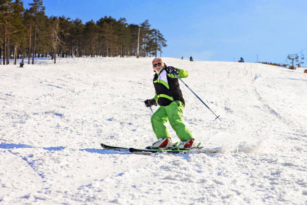 Vital, active senior men snow skier. Enjoying on sunny ski resorts. Aging with attitude. At the top of the high snowy mountain.