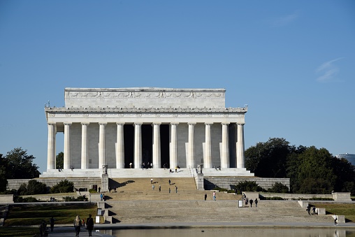 A long exposure of the Lincoln Memorial at Dusk. The monument is crowded with people coming and going. The colorful sky is seen above as the sun is going down.