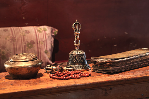 Typical items from a Tibetan Buddhist monastery: Tibetan bell, a thunderbolt (Vajra or Dorje), an old prayer book and prayer beads. Vajra is a Sanskrit word meaning both thunderbolt and diamond.