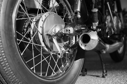rear wheel with spokes and chromed exhaust of a vintage motorcycle