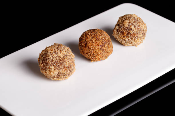 Beautiful candy truffle on a white plate on a black background close up