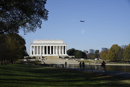 A jetliner flies over the Lincoln Memorial and reflecting pool as it approaches its landing  at Ronald Reagan National Airport.
