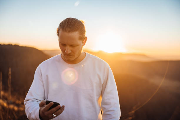 Bad News Young Man Reading Messages on Mobile Phone in Sunset Light stock photo