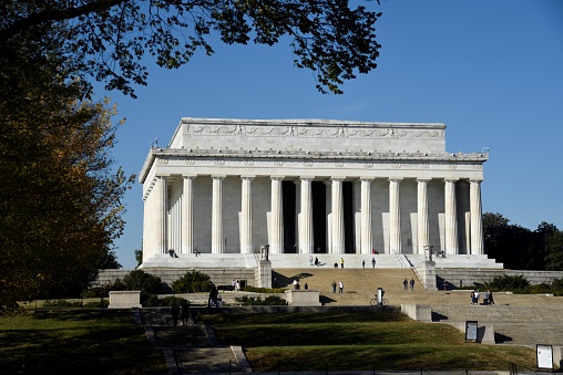 A long exposure of the Lincoln Memorial at Dusk. The monument is crowded with people coming and going. The colorful sky is seen above as the sun is going down.