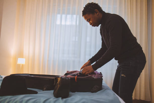 un jeune homme afro-américain faisant ses valises pour un voyage - vanity business business person men photos et images de collection