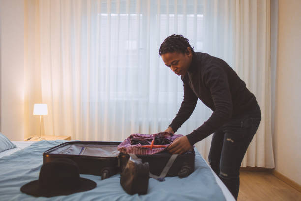 un jeune homme afro-américain faisant ses valises pour un voyage - vanity business business person men photos et images de collection