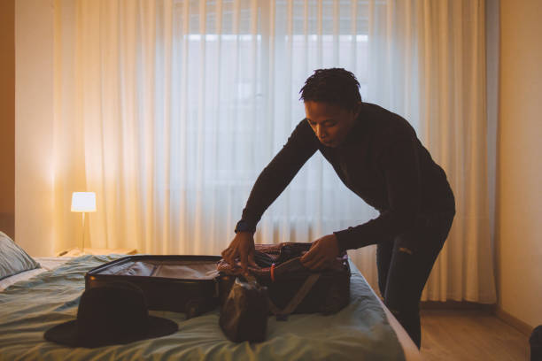 un jeune homme afro-américain faisant ses valises pour un voyage - vanity business business person men photos et images de collection