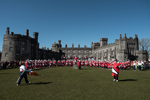 Kilkenny, Ireland - 03/16/2022. Band performance with flag-throwers, cheerleaders at Kilkenny castle during the Kilkenny St.Patrick Festival 2022
