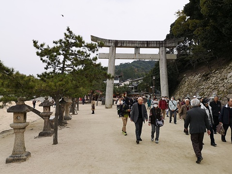 March 25, 2019 - Hiroshima, Japan: tourist and locals walking  below Itsukushima Shrine stone torii