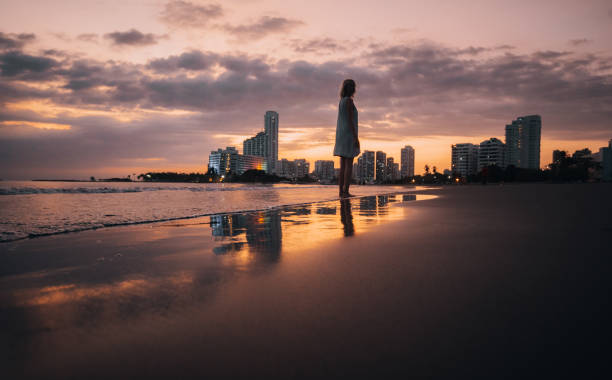 A young woman walks and enjoys a beautiful sunset on the beach.