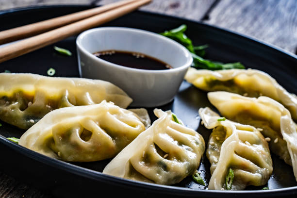 istock Gyoza - delicious dumplings filled with vegetables, wrapped into thin dough served with soy sauce on wooden table 1385836480