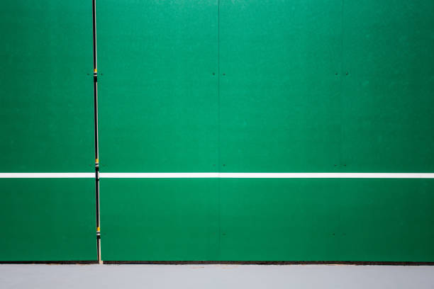 Tennis court practice hitting wall with white strip at net height.