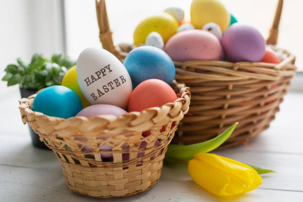 istock Wicker baskets with bright colorful eggs and with text Happy Easter and flower 1385845635