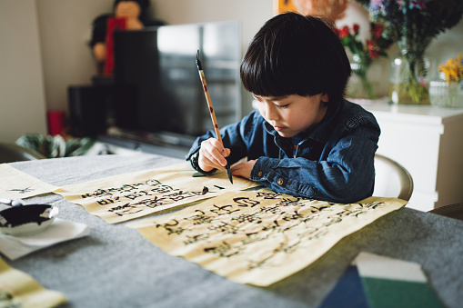 Asian Chinese boy learning Chinese calligraphy at home.