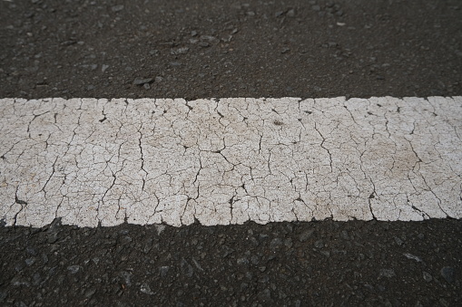 Close up of road mark on black cracked asphalt concrete