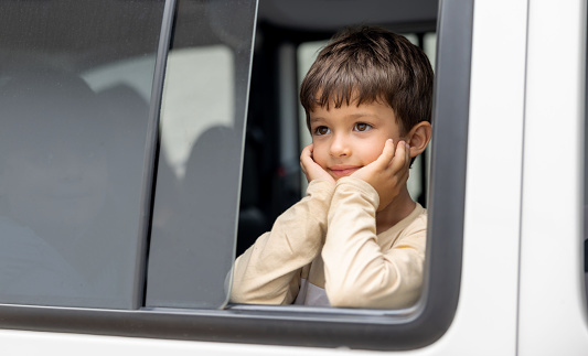 Portrait of a thoughtful Brazilian boy inside a car and looking through the window
