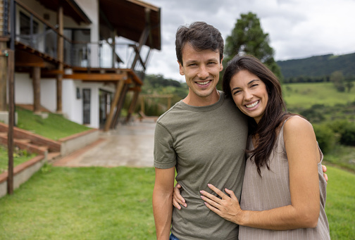 Portrait of a loving Brazilian couple outside their house in the countryside and looking at the camera smiling