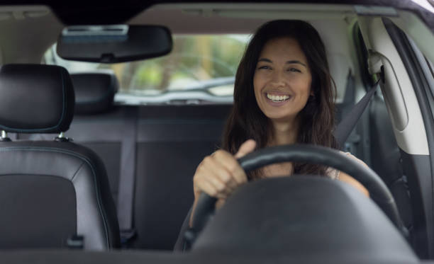istock Happy woman smiling while driving a car 1385872142