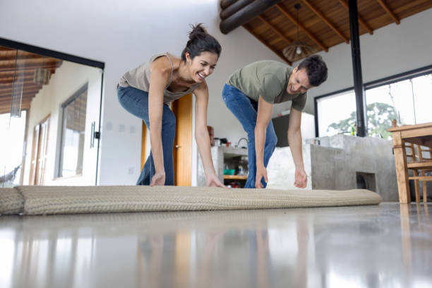 istock Happy couple having fun unrolling a carpet at home 1385872179
