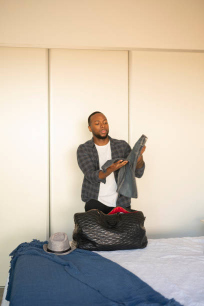 istock Black man packing luggage with garments  at  bedroom 1385877253