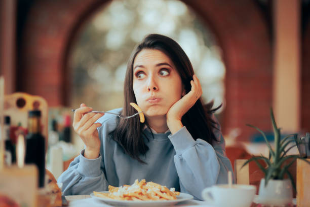 mujer estresada comiendo en exceso una gran porción de papas fritas - guilt female women one woman only fotografías e imágenes de stock