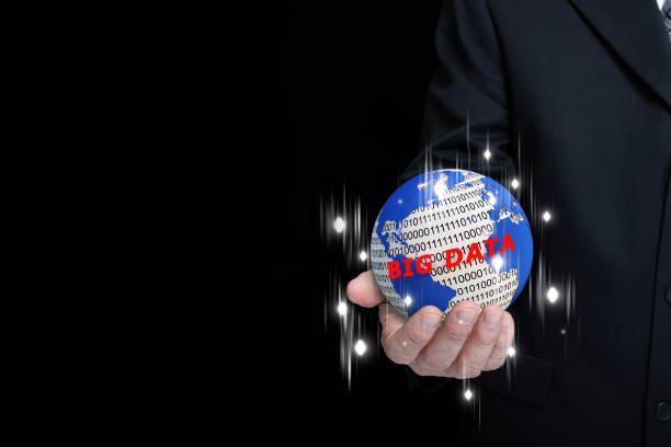 A businessman holding a globe with map, binary numbers, big data text, and streaks of light. Technology and big data concept.