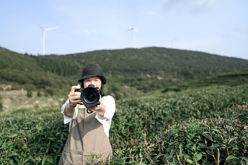 Young  asian woman taking photo of scenic view of organic tea plantations