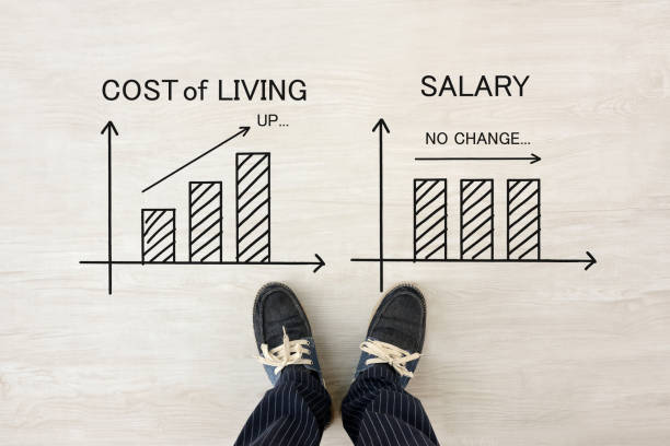 Man' feet with shoes and cost of living and salary transition graphs stock photo