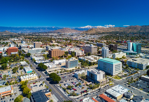 Downtown Riverside skyline aerial view with Blue Mountain (center), Box Springs Mountain (right), and the partially snowcapped San Bernardino Mountains in the far distance.  Riverside is located in the Inland Empire region of the Greater Los Angeles area.