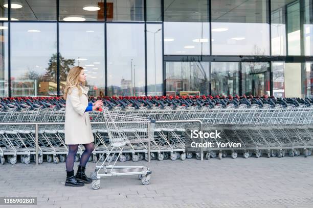 Woman In Front Of The Mall Pushing Shopping Cart Stock Photo - Download Image Now - Shopping Cart, Supermarket, Parking Lot