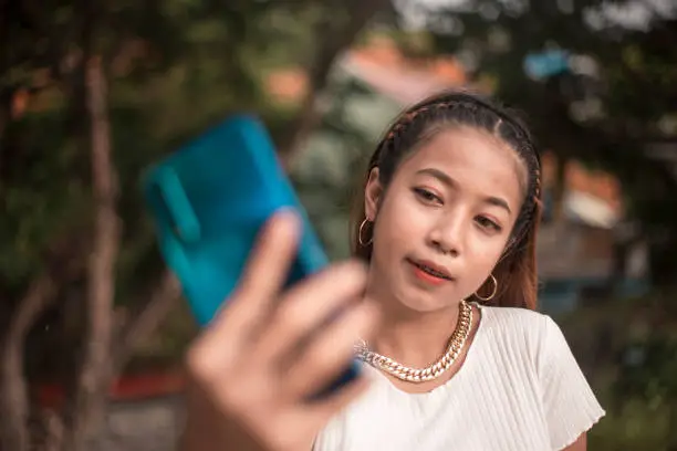 Photo of A young woman takes an angled selfie of herself. A rebellious look with a nose ring and a large bling necklace.