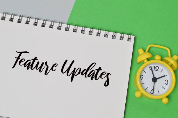 istock Top view of clock and notebook written with FEATURE UPDATES. 1385905993