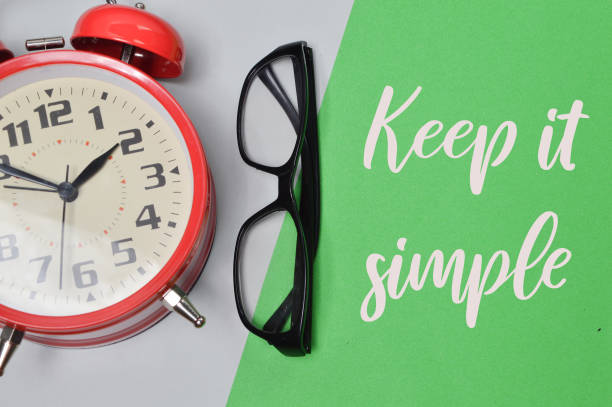 istock Top view of clock and eyeglasses on green background written with KEEP IT SIMPLE 1385906048