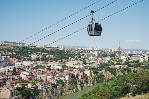 Cable road over old Tbilisi town on Kura river background