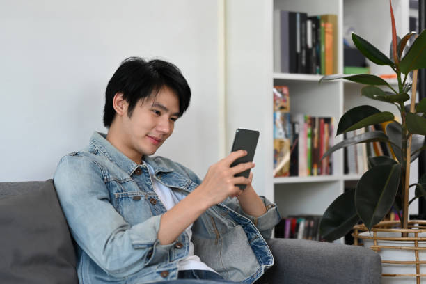istock Happy asian man using cellphone for checking email or social media on internet at home. 1385907678