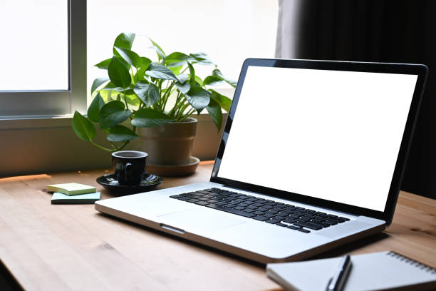 istock Mockup laptop computer, coffee cup, notebook and houseplant on wooden table. Blank screen for graphics display montage. 1385907760
