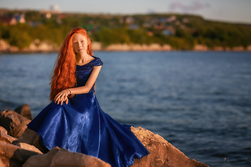 girl with red hair greets the sunrise on the seashore