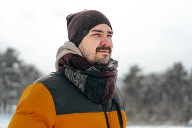 istock Young man in warm coat standing in snowy winter forest 1385912922