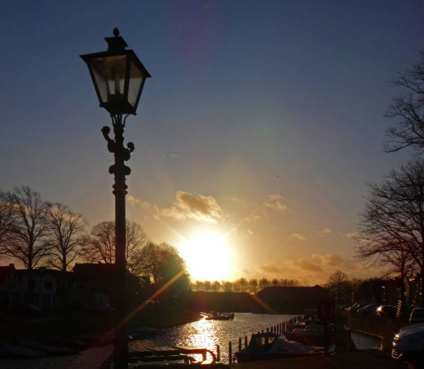 The last sunbeams of the day on an old lamppost in the historical significant town Brielle, the Netherlands. The sun is reflected in the water