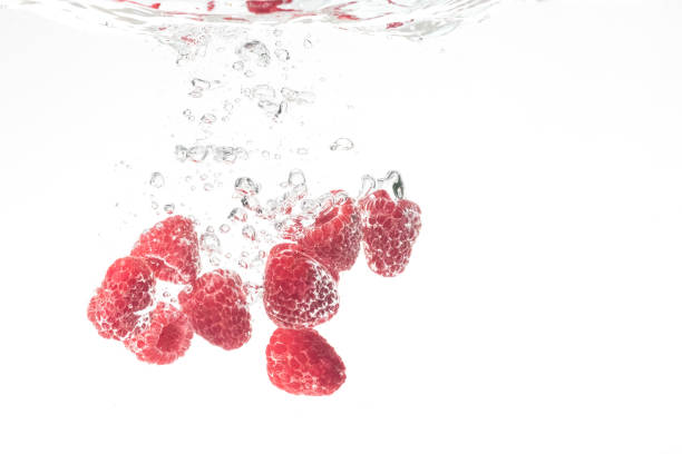 istock Raspberries splashing in water on white 1385914805