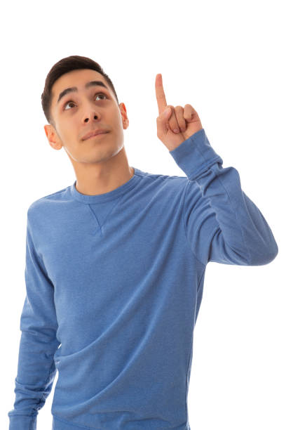 Handsome looking mixed race teenager pointing up on cut out white background