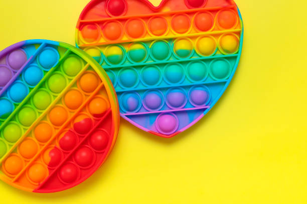 istock Popular silicone multi-colored anti-stress toy pop it on yellow background flat lay top view. Trendy modern sensory children's toy, fidget push pop it 1385916626