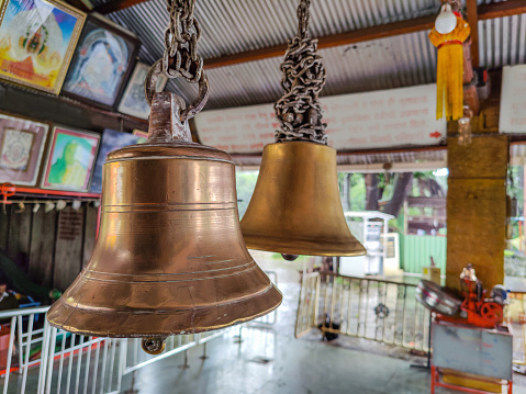 Stock photo of two anicnet big size copper or bronze metal bell hanging in the hindu temple on blur background. Picture captured under natural light at Kolhapur, Maharashtra, India. focus on object.