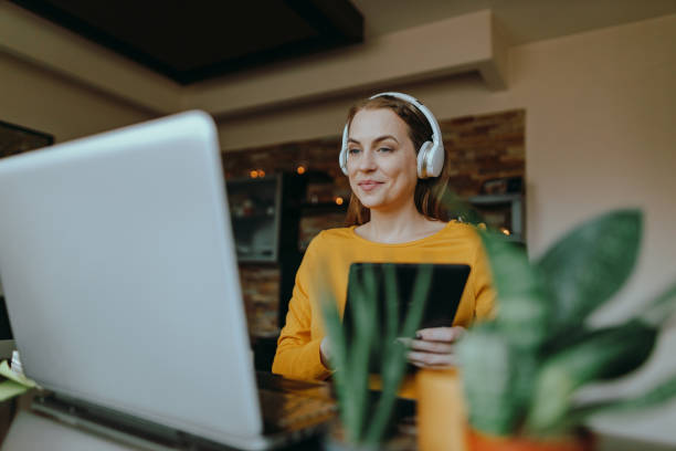 Woman using a laptop and a digital tablet working from home