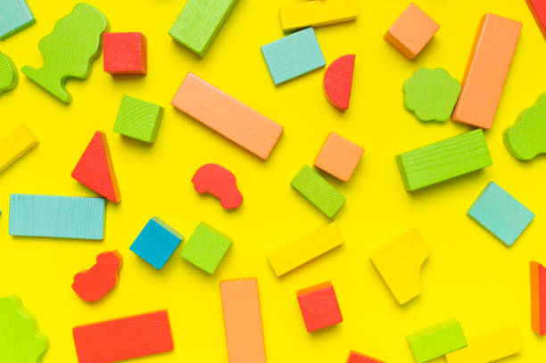 istock Multi-colored children's constructor made of natural wood on bright yellow background flat lay top view. Colored children's bricks for construction. Building blocks background. Developing toys, game 1385920192