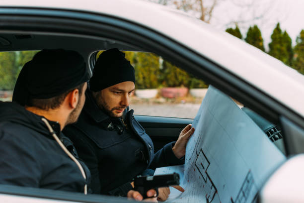 istock Two Thieves parked in an ally waiting while talking on the phone, observing their target and loading their guns. 1385920292