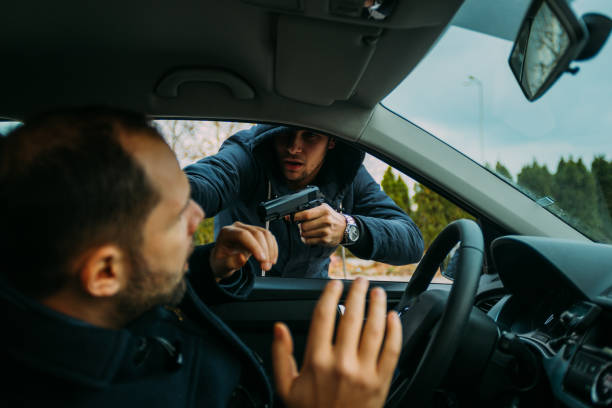 istock Carjacker aggressively attacking a car owner with a gun, trying to extort money. 1385920550