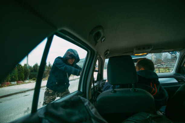 istock Carjacker aggressively attacking a car owner with a gun, trying to extort money. 1385920561
